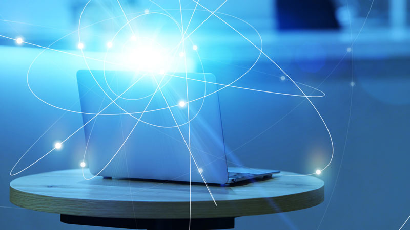 Computador portátil em cima de uma mesa, em fundo azul, com uma ligação à internet ultrarrápida